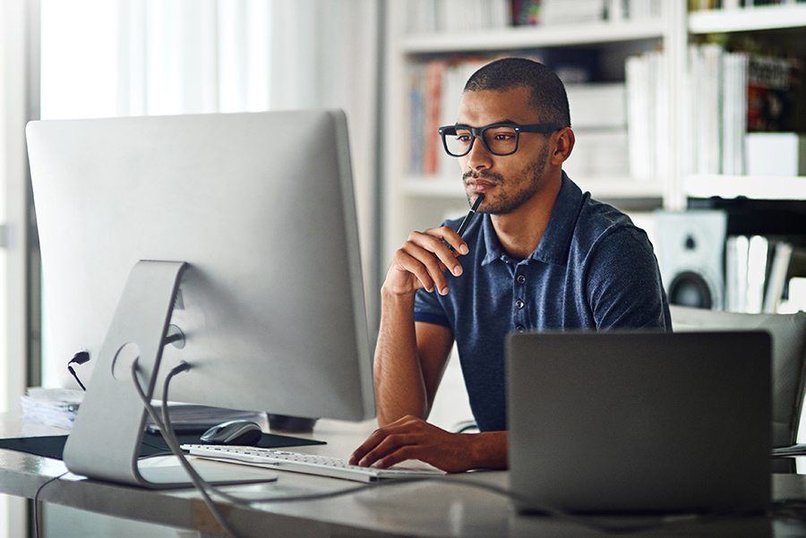 A young man analyzing data on a desktop computer.