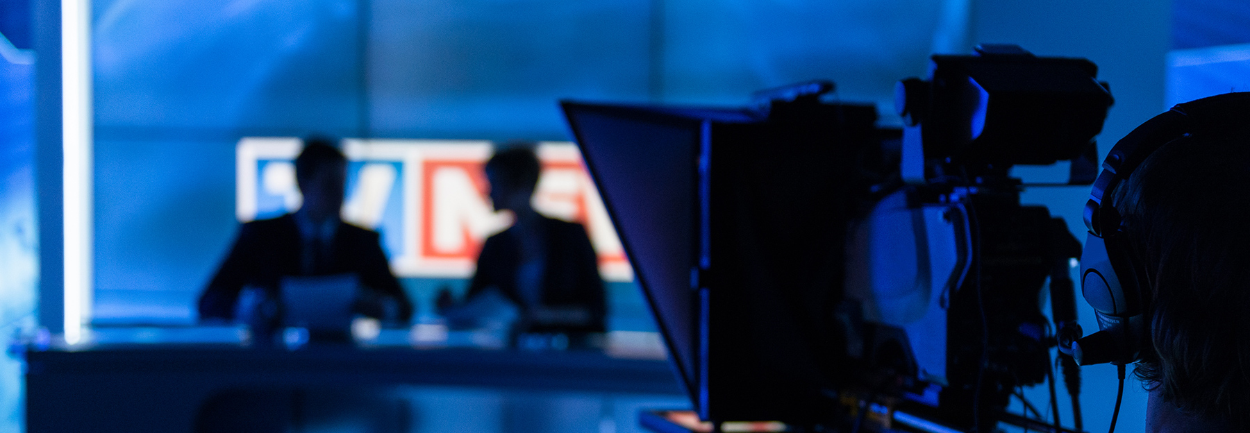 A dark lit newsroom with the anchors ready, moments before the show goes "live".