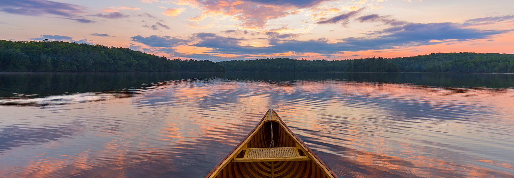 A wooden canoe out in its element on a serene lake.
